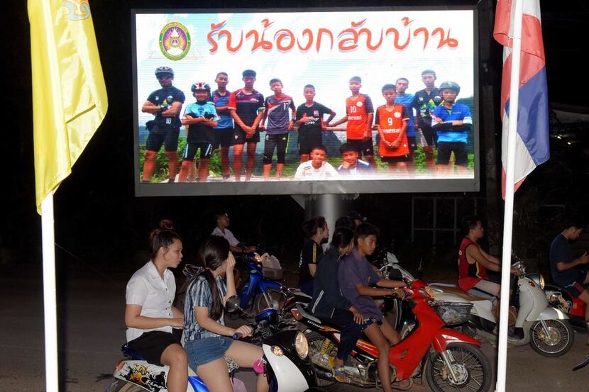 Motorists pass by a billboard displaying a photograph of the Thai children's football team...