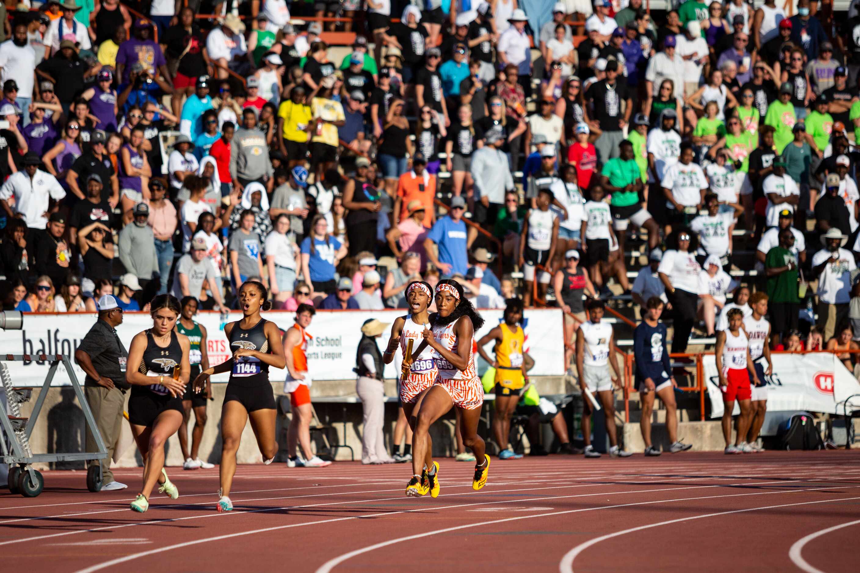 Lancaster’s Jalyn Williams passes the baton at the hallway mark of the girls’ 4x200 relay to...