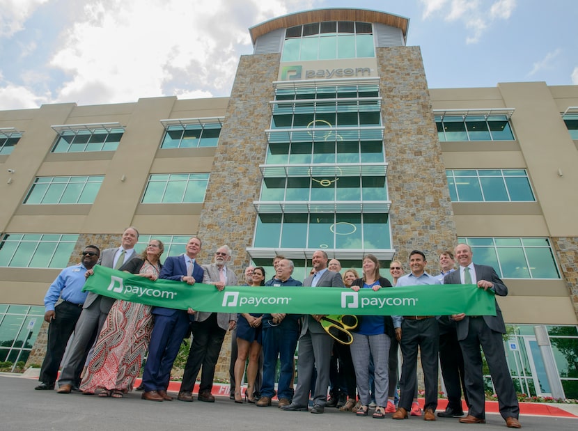 Paycom CEO Chad Richison, holding giant scissors, is joined by Grapevine city officials...