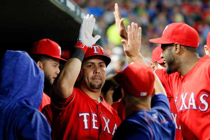 Texas Rangers' Carlos Beltran, center is congratulated in the dugout after hitting a solo...