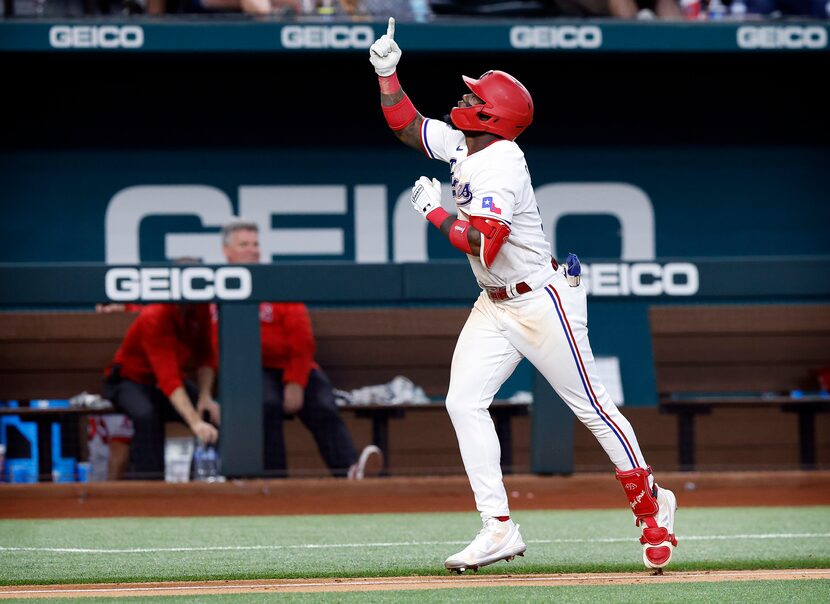 Texas Rangers batter Adolis Garcia points skyward as he heads for home on a two-run homer, a...