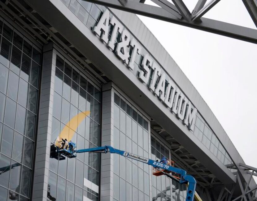 
Mike Oliver and Art Modesto apply the beginnings of the College Football Playoff logo to...