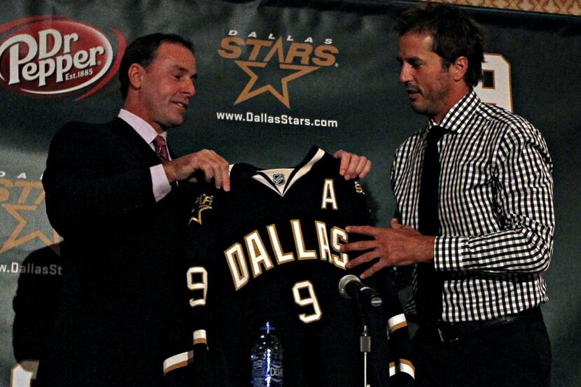 Dallas Stars general manager Joe Nieuwendyk (left) hands Mike Modano a jersey during a press...