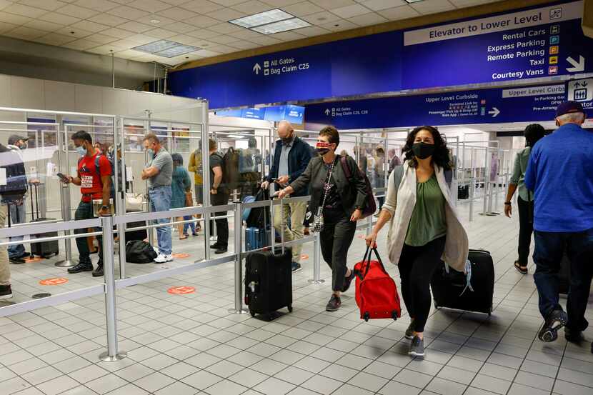 Travelers walk past a TSA checkpoint in Terminal C at DFW International Airport on Oct. 20,...