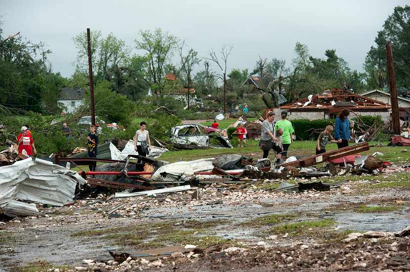 Residents pick their way over the rubble near the middle school on Monday, May 11, 2015, in...