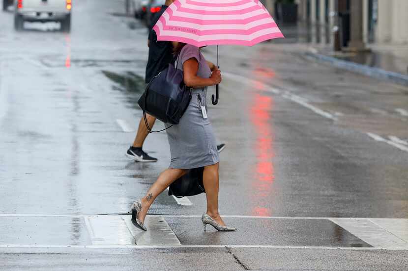 A pedestrian avoids the rain with an umbrella during a thunderstorm in downtown on Tuesday,...