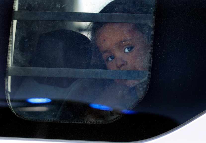A young girl peers out a van window as she and other migrants leave Border Gate 42 in El...