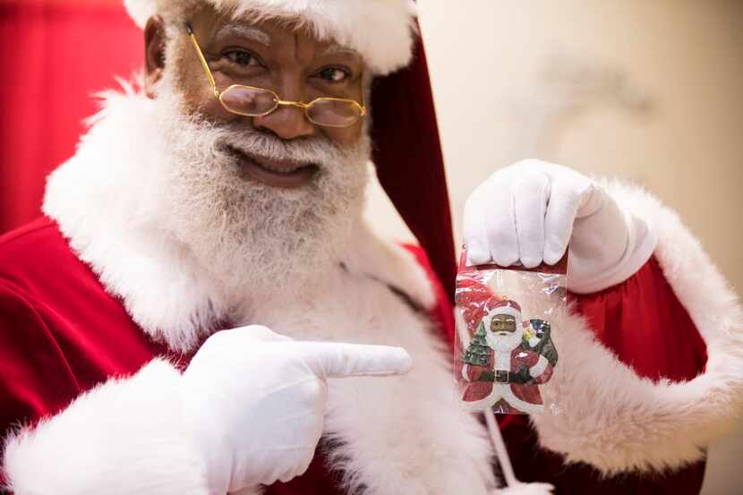 Santa Larry Jefferson holds up some "multicultural" Santa merchandise for sale at the Santa...