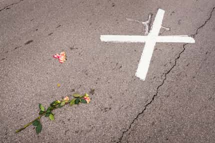 Flowers flattened by passing traffic rest next to the "X" marking the spot where President...
