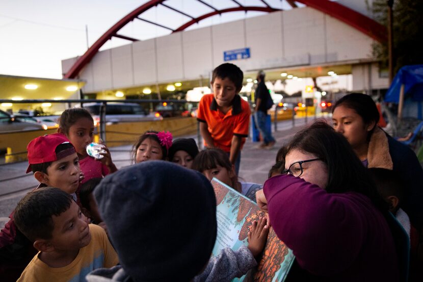 A Houston volunteer (right) reads to a group of asylum-seeking children by the Gateway...