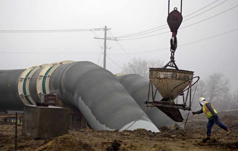 A worker guides equipment into place at the construction site for pipes that will carry...