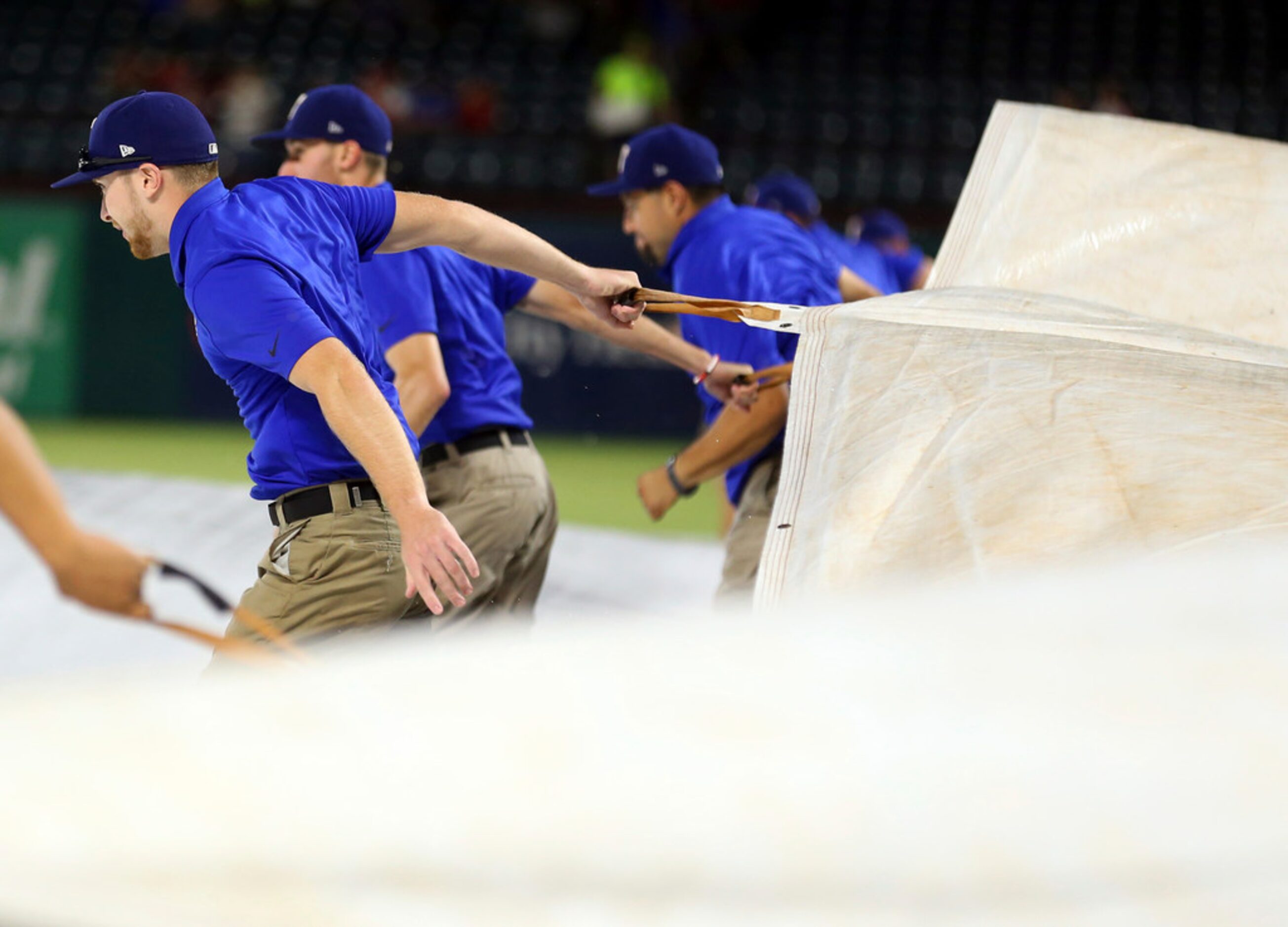 The grounds crew removes the tarp from the infield before a baseball game between the Los...