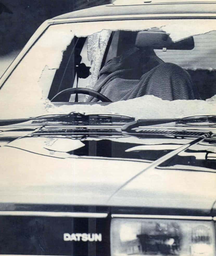 A blanket covers a body at the wheel of a car with shattered windows on Aug. 19, 1987, in...