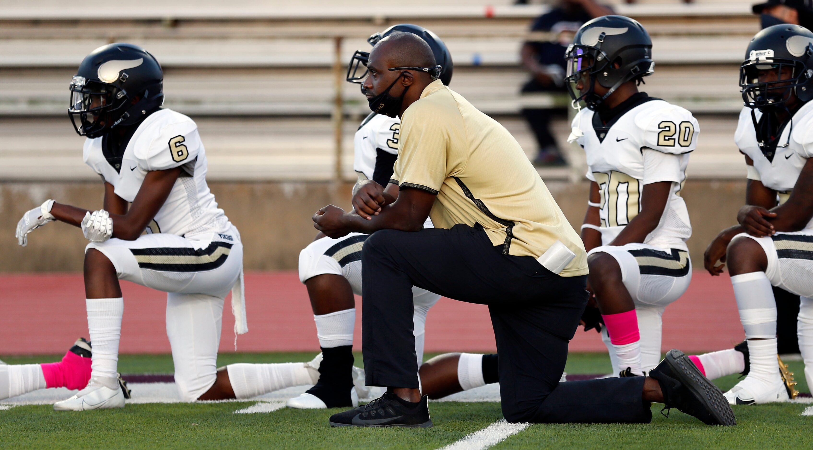 Pinkston head coach Derek Lewis and his football players take a knee for the national anthem...