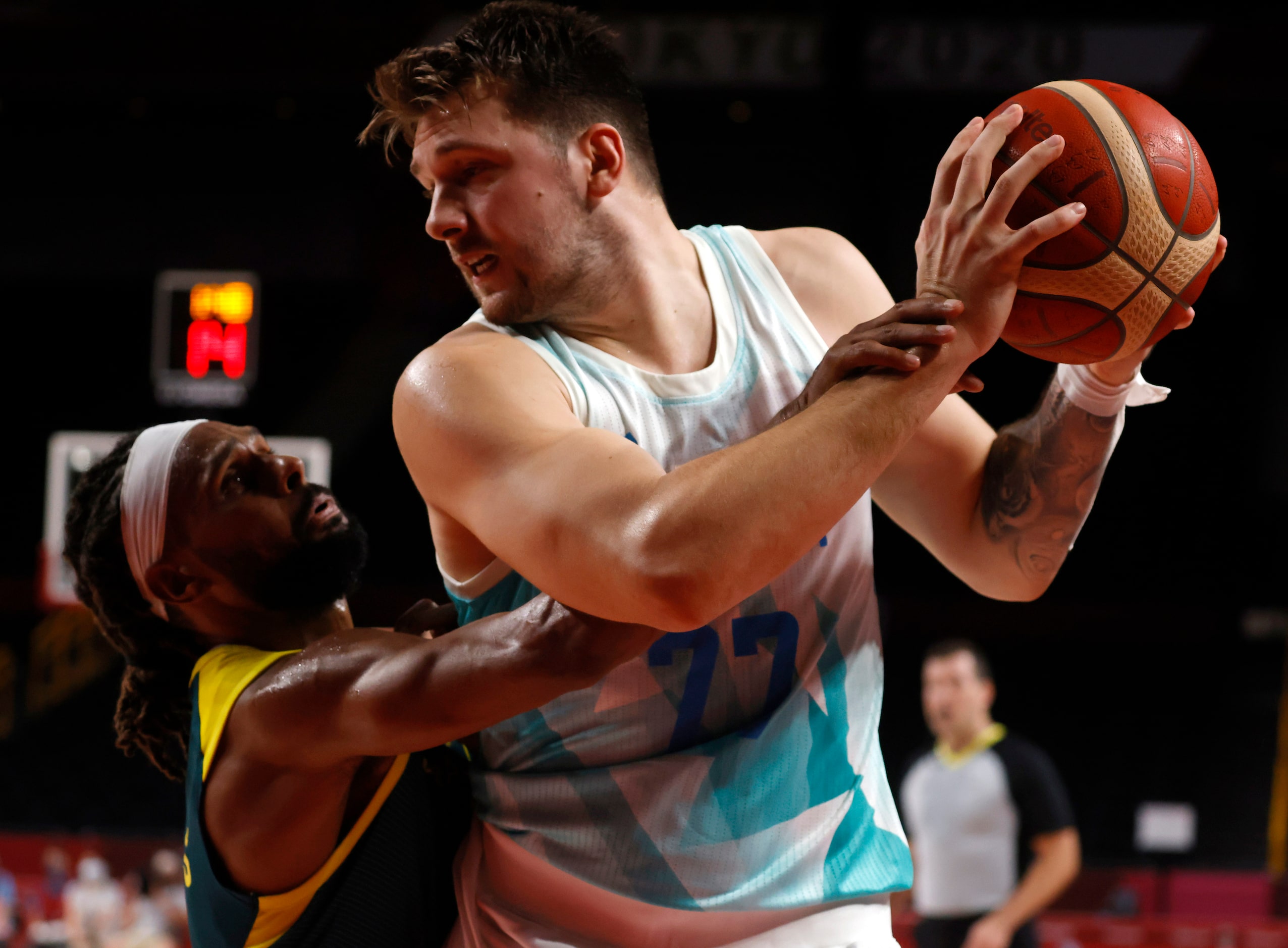 Slovenia’s Luka Doncic (77) looks to post up Australia’s Patty Mills (5) as he defends...