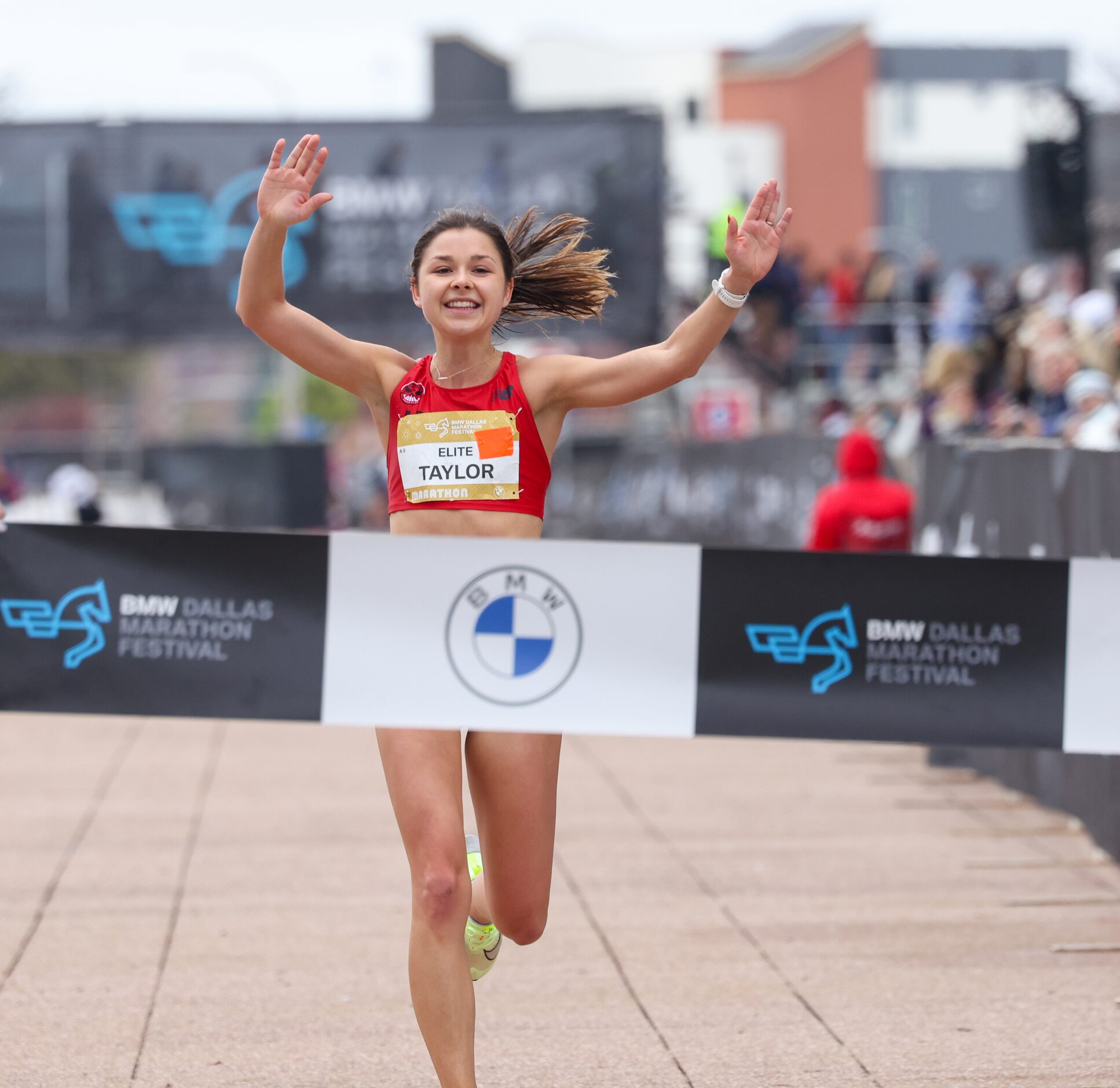 Megan Taylor raises her arms as she crosses the BMW Dallas Marathon finish line on Sunday,...