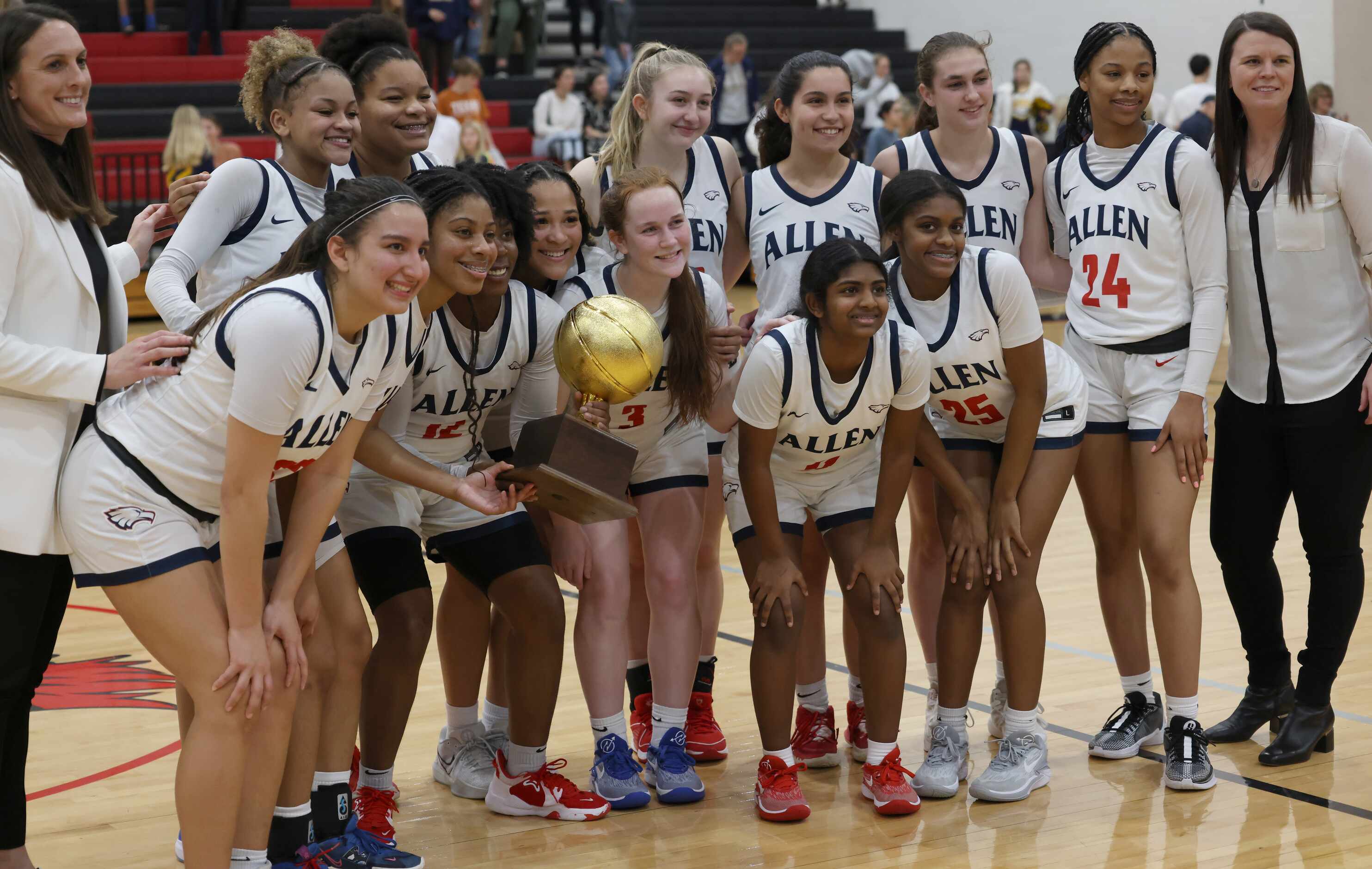Allen players and coaches pose with their trophy following their 6A area round victory over...