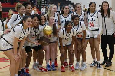 Allen players and coaches pose with their trophy following their 6A area round victory over...