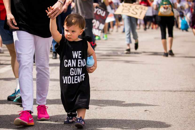 18-month-old Henry Ayers wears a shirt reading "We Can End Gun Violence" as he walks with...