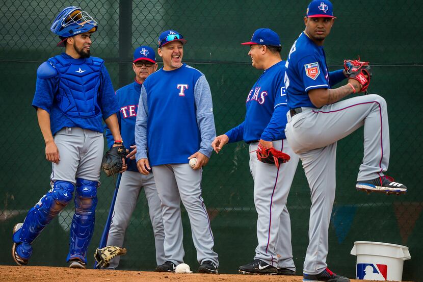 Texas Rangers bullpen coach Hector Ortiz (center) laughs with catcher Robinson Chirinos...