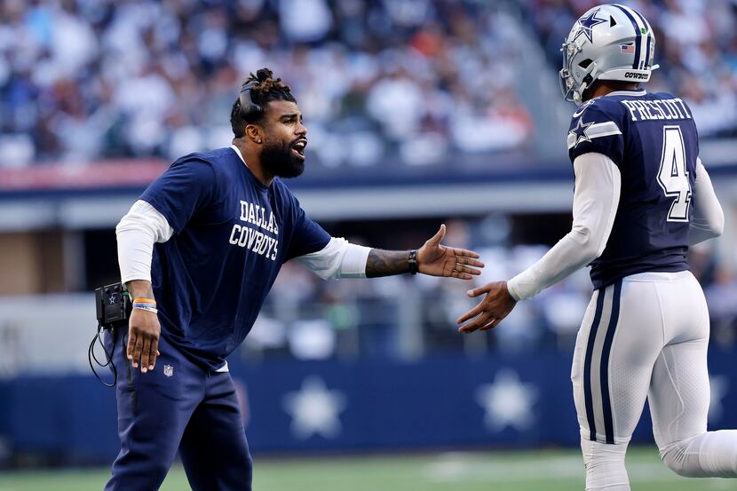Injured Dallas Cowboys running back Ezekiel Elliott (left) congratulates quarterback Dak...
