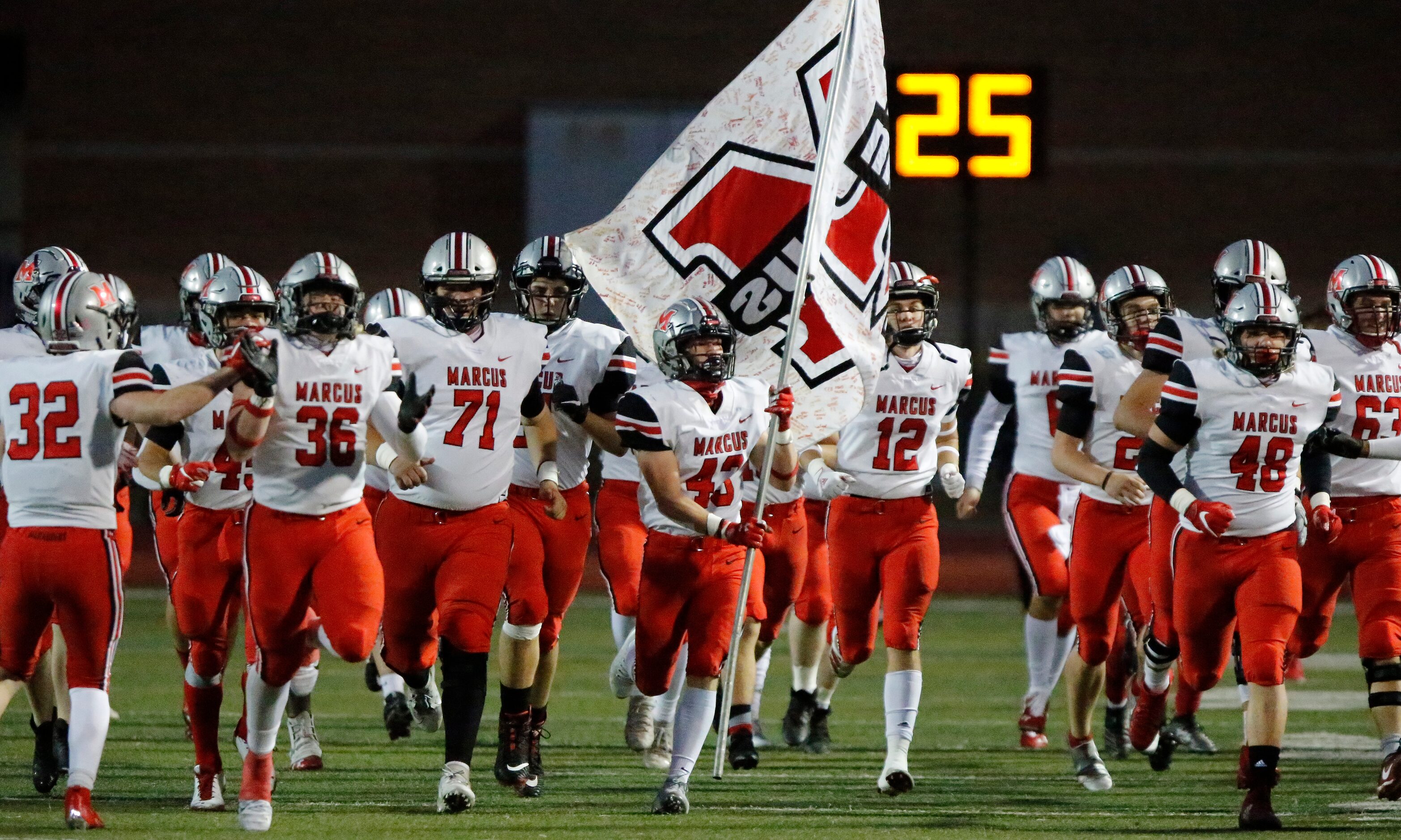 Flower Mound Marcus linebacker Mark Vassar (43) carries the school flag onto the field as...