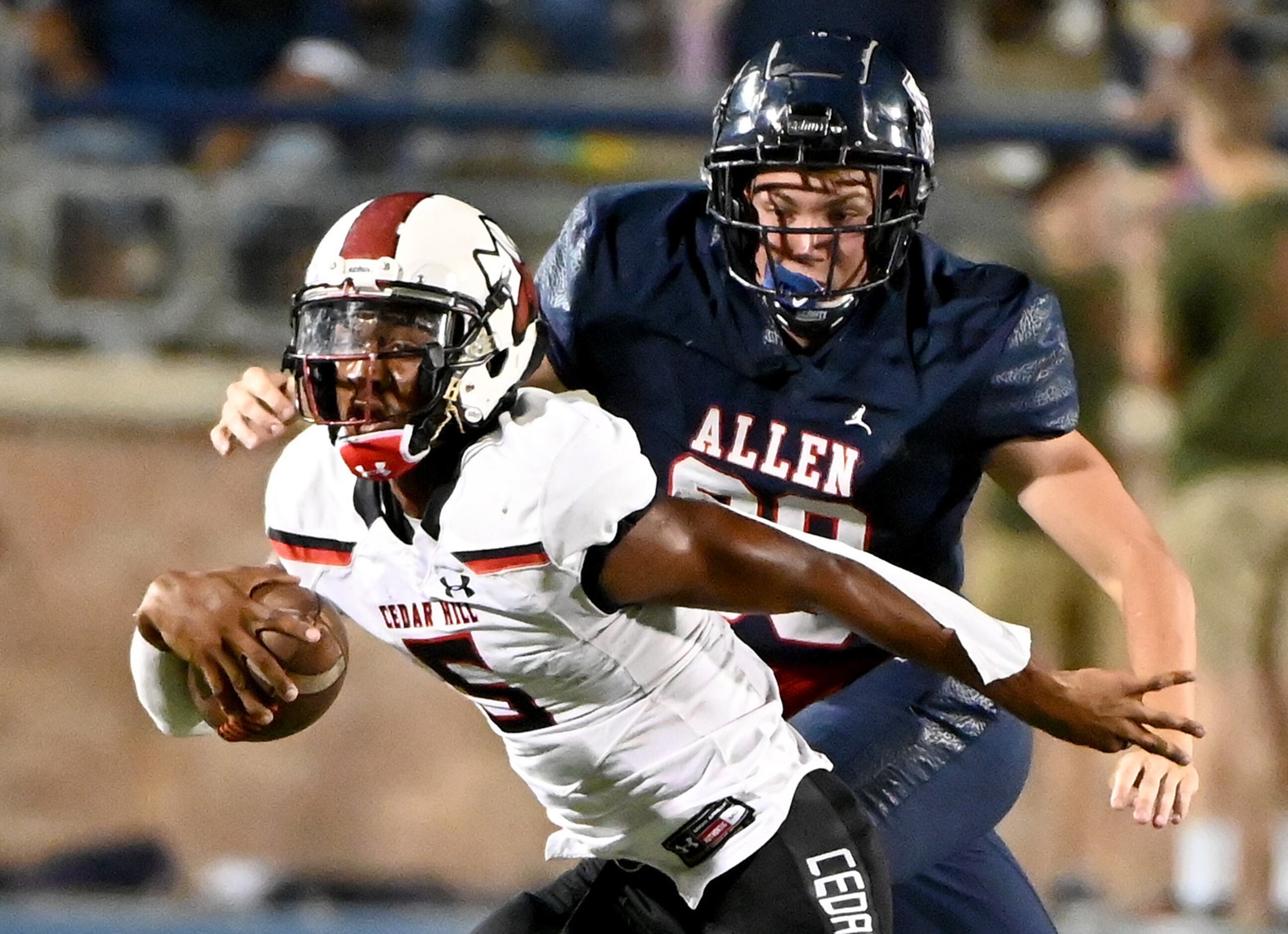 Cedar Hill's Cedric Harden Jr. (5) tries to get away from a tackle attempt by Allen’s Blake...