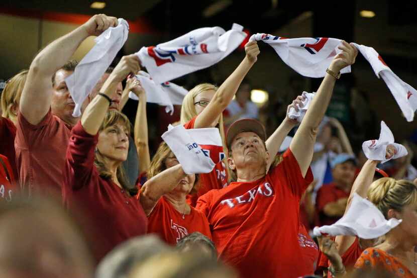 Rangers fans try to rally the troops in the bottom of the ninth inning in Texas' 5-1 loss...