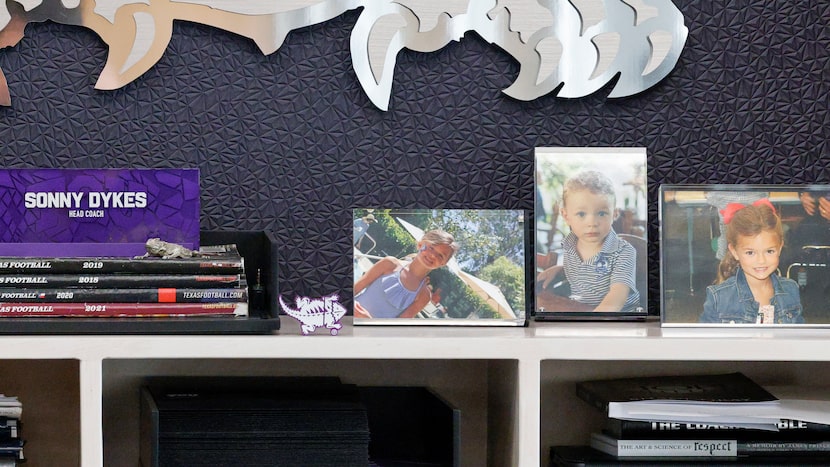 Pictures of TCU head coach Sonny Dykes’ children sit behind the desk in his office at Amon...