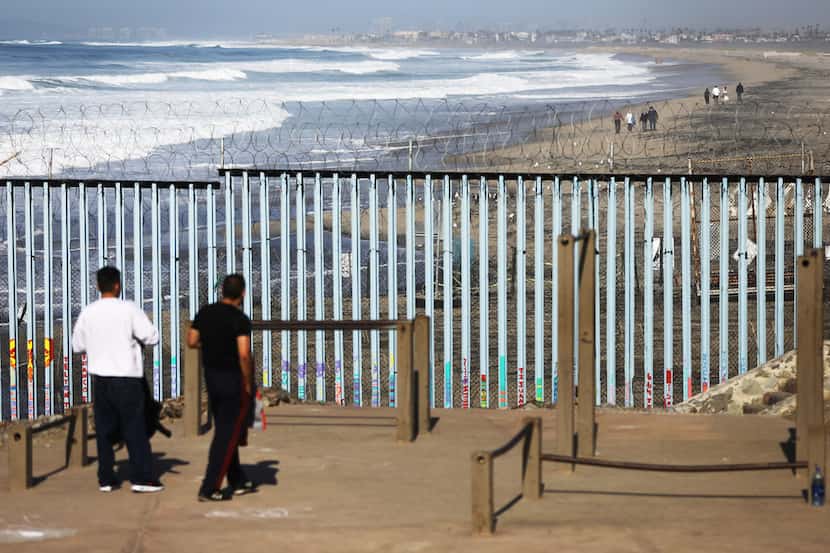  People stand on the Mexican side of the U.S.-Mexico border on Jan. 10, 2019 as seen from...