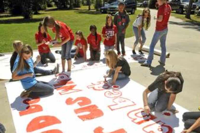  Kountze High School cheerleaders and other children worked on a large sign Wednesday in the...