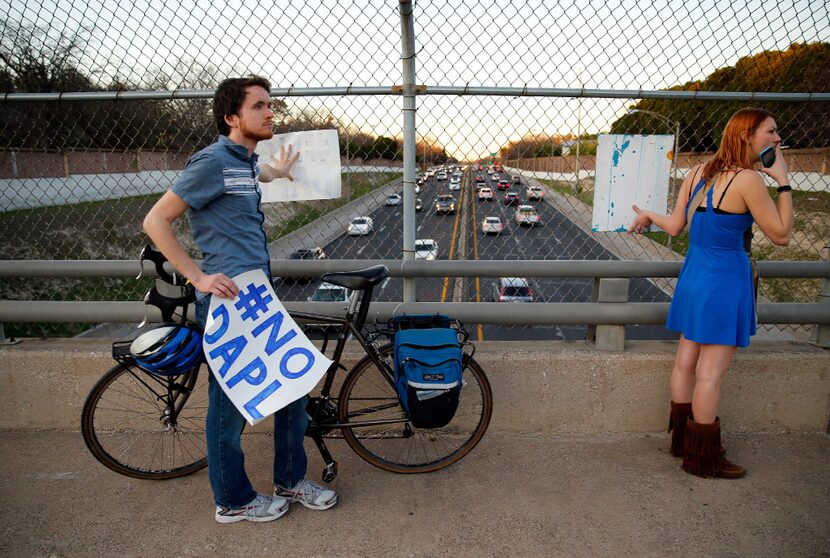 Dakota Access pipeline protesters Tim McCarthy and Desiree Graham held up signs over the...