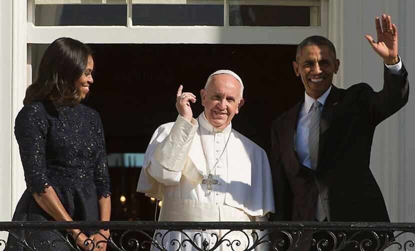 Pope Francis, accompanied by first lady Michelle Obama and President Barack Obama, waves...