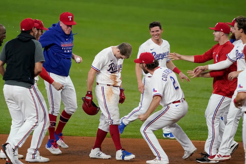 Texas Rangers' Brock Holt, center left with head down, Charlie Culberson (2) and the rest of...