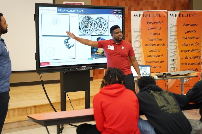 Toyota team member Kandro Brown points to a large TV screen during a presentation in...