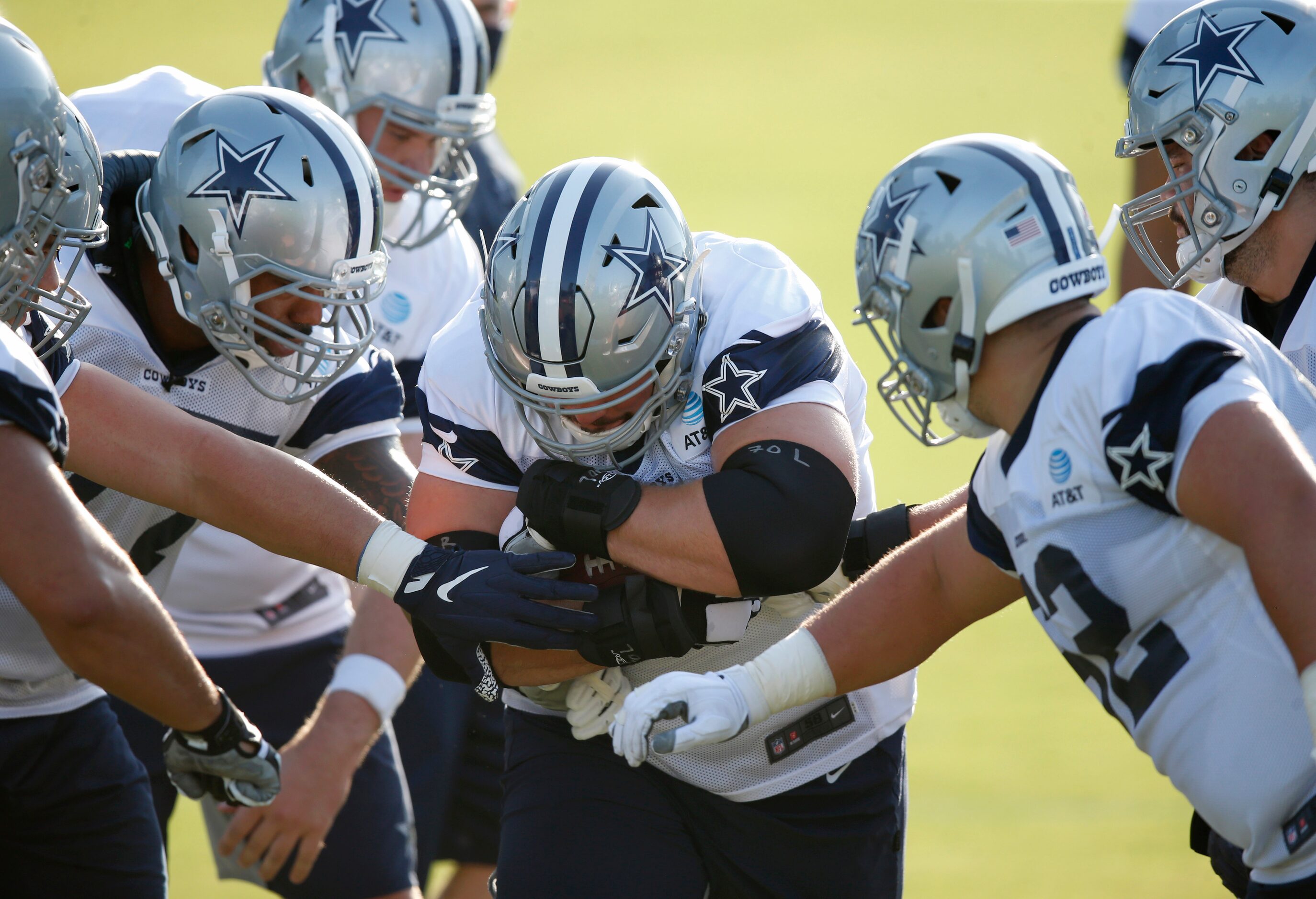 Dallas Cowboys guard Zack Martin (70) holds the ball tightly as he runs through a gauntlet...