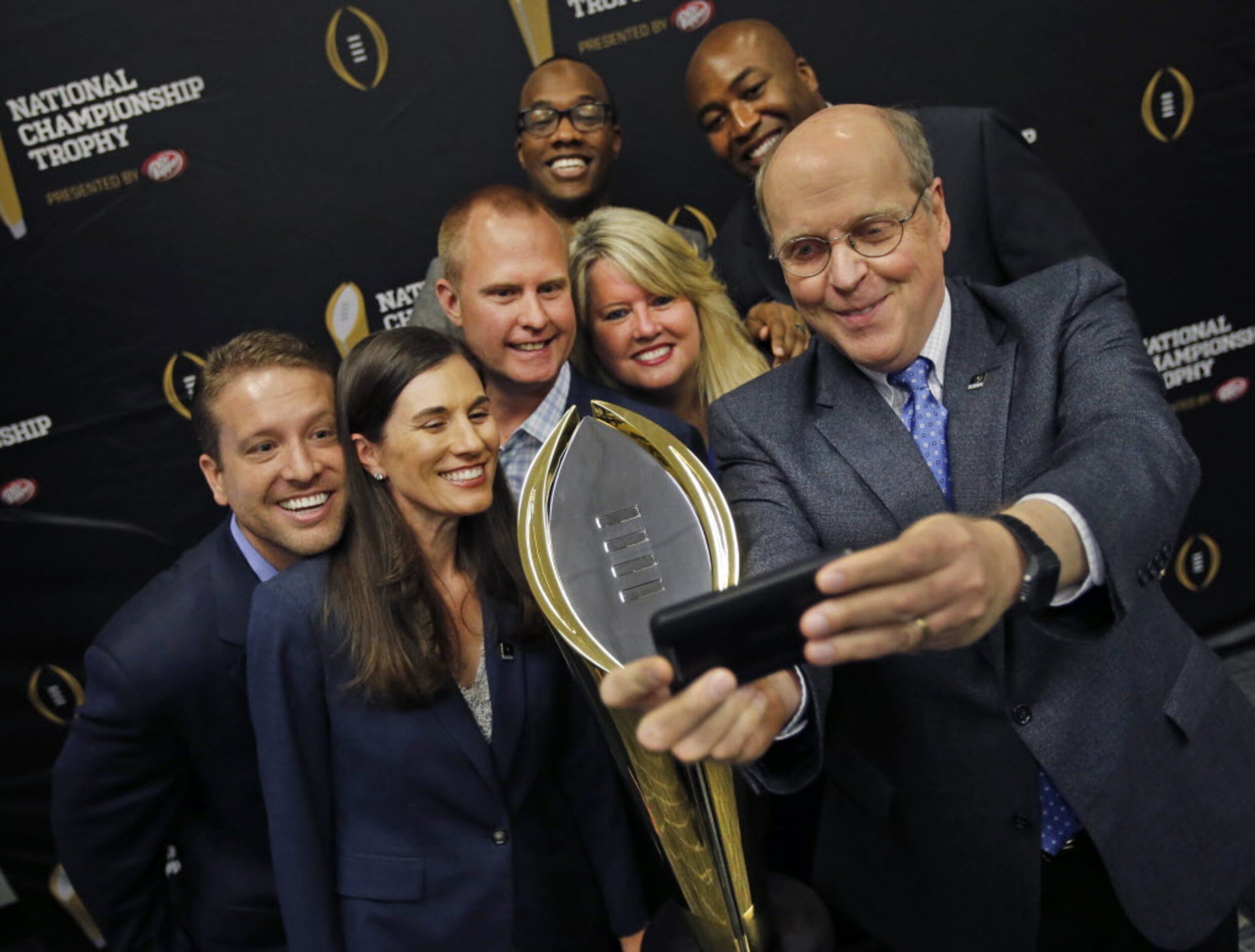 College Football Playoff executive director Bill Hancock, right, takes a 'selfie" with, from...