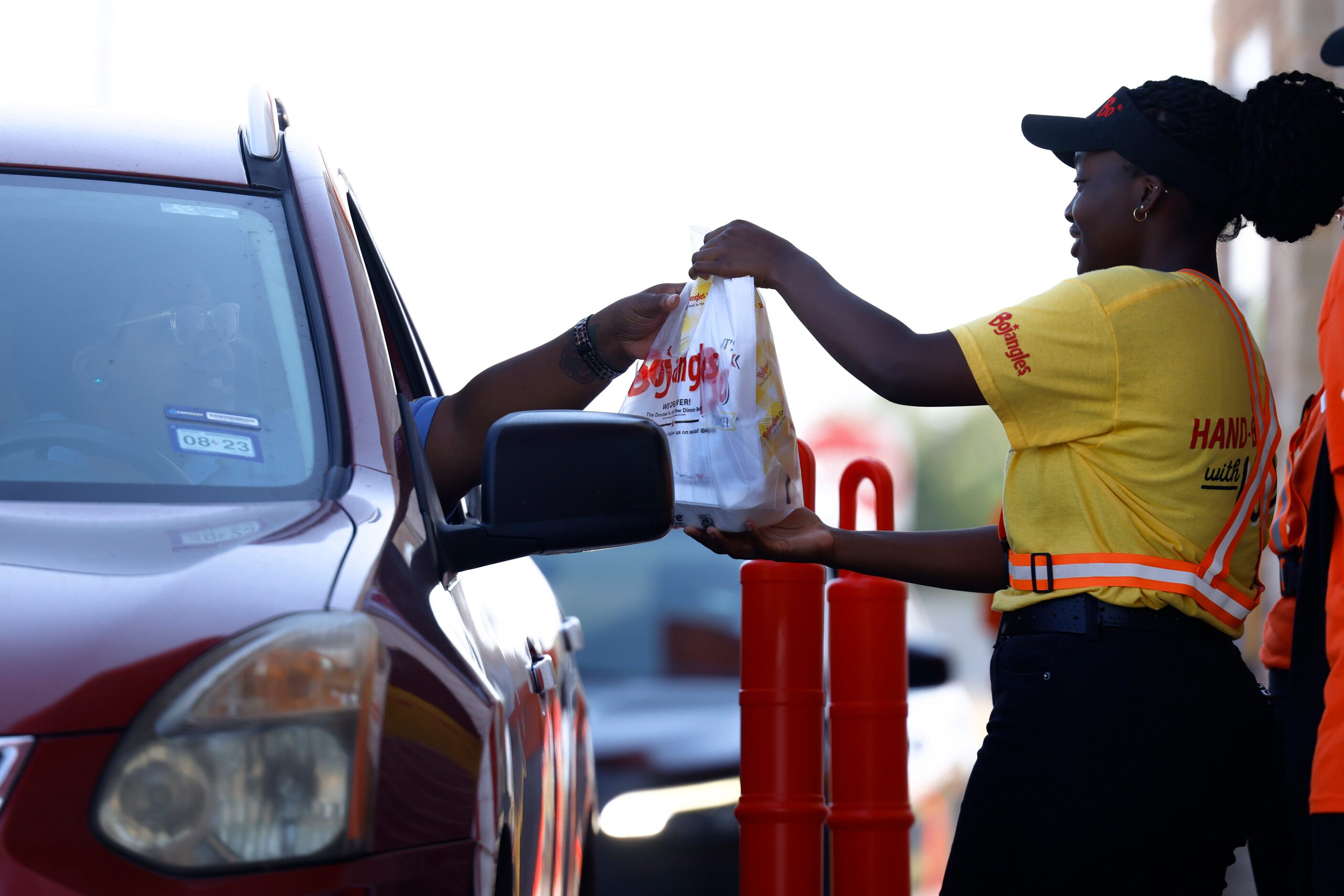 Employee Emike Anaani provides a drive-through order during the opening day of Bojangles in...