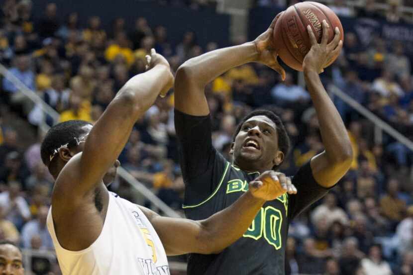 Baylor's Royce O'Neale, right, looks to shoot as West Virginia's Devin Williams defends...