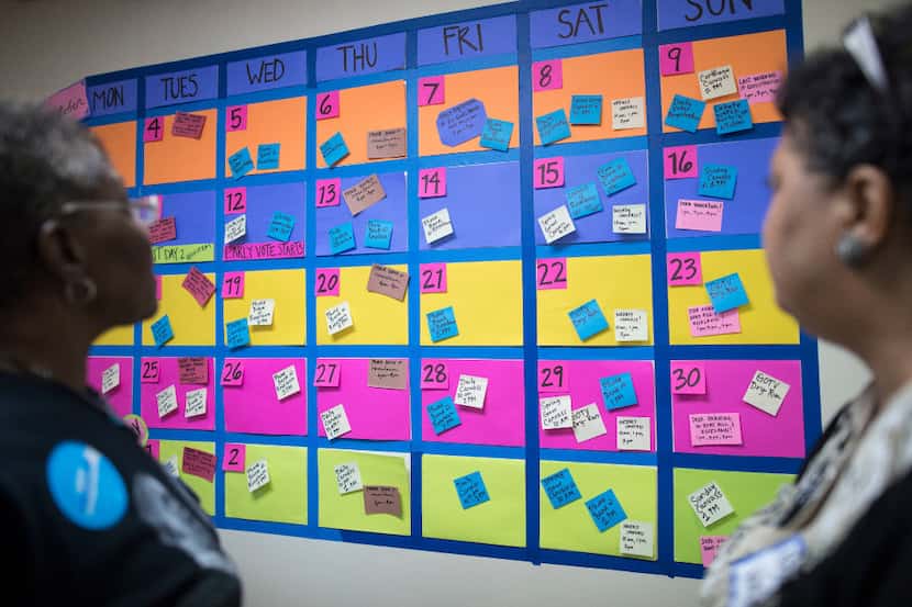 Supporters inspect a wall calendar of get-out-the-vote and voter registration activities at...