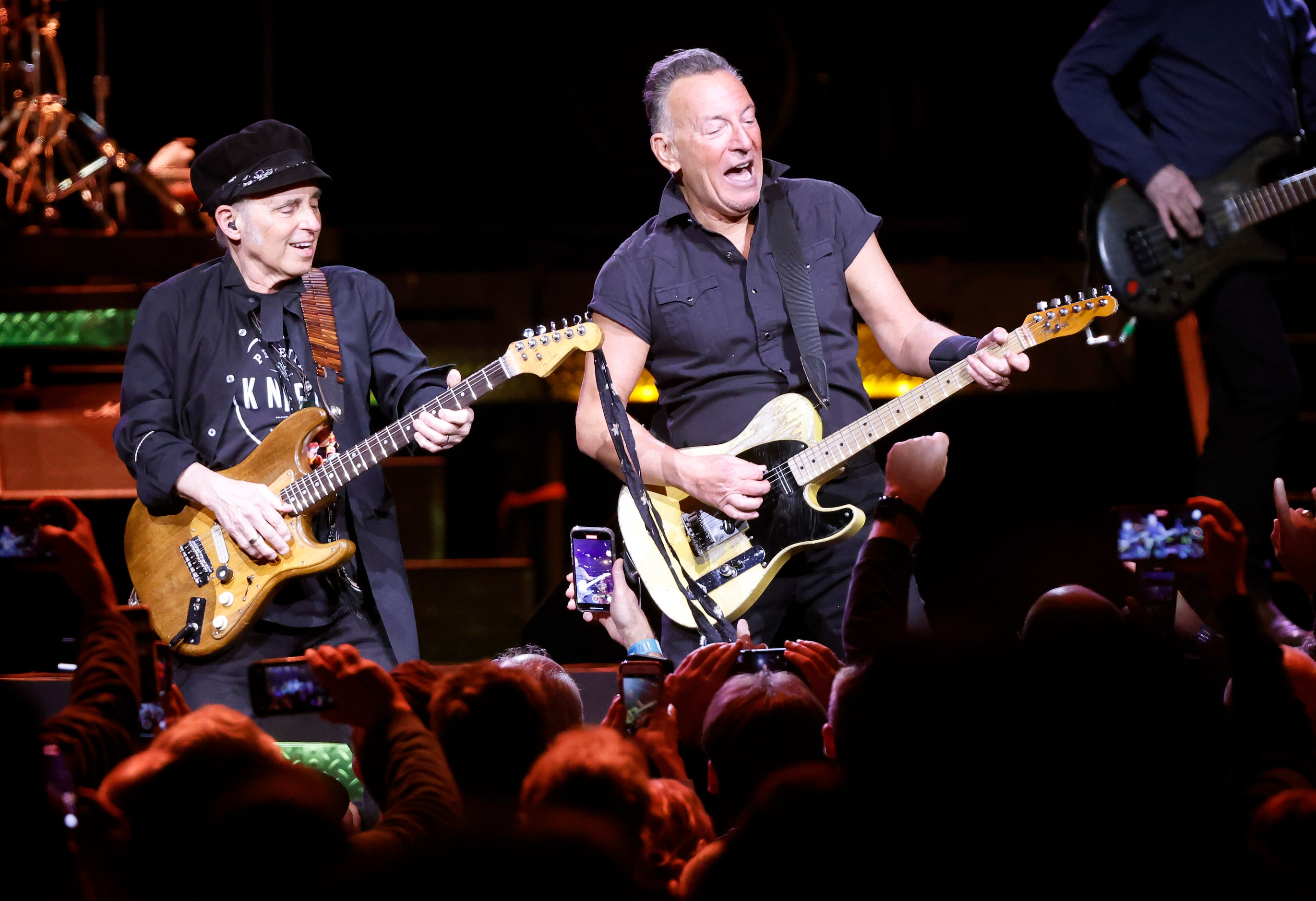 Clad in a black pearl snap shirt and black pants, Bruce Springsteen (right) performs with...