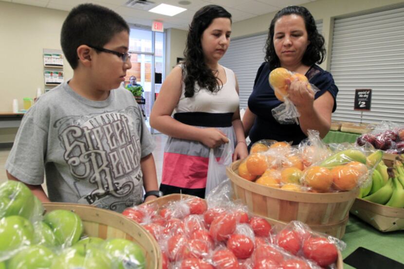 Irma Castañeda (right) shops for fresh fruits and vegetables with her children, Brenda and...