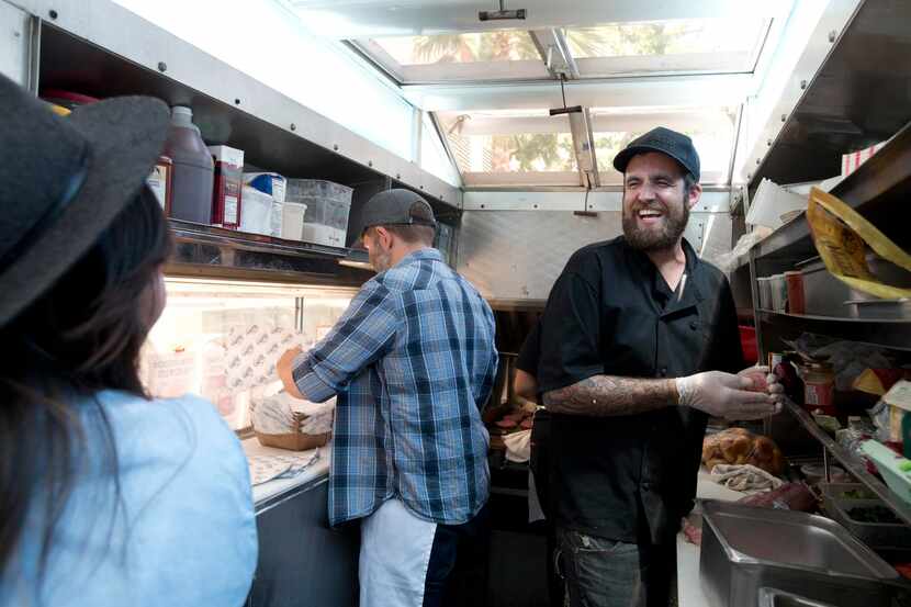 
Employee Kyle Snavely (right) jokes with food truck owners Diana and Ryan Lamon as they...