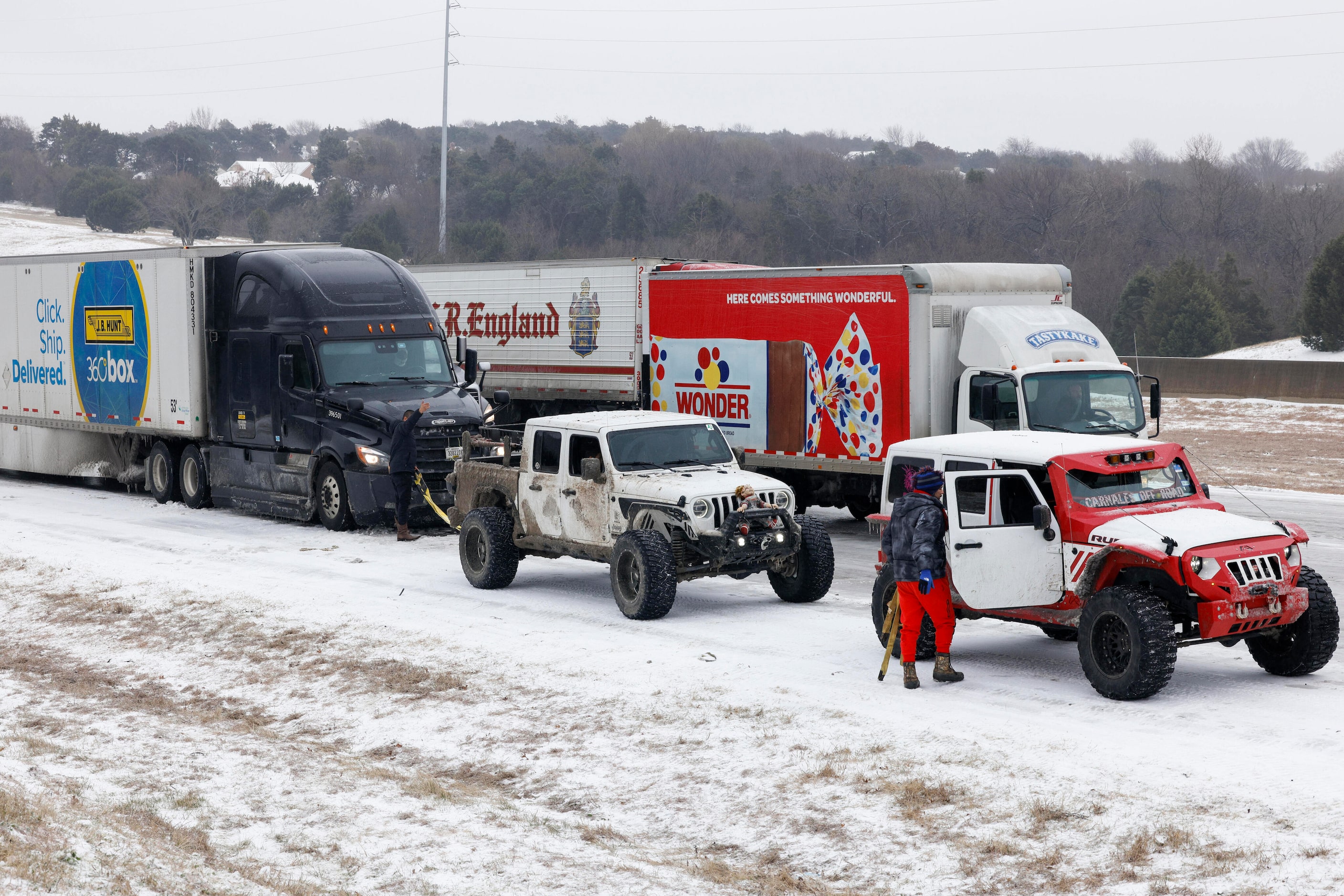 Members of the Carnales Off Road Jeep club work to pull a semi-truck up an ice covered hill...