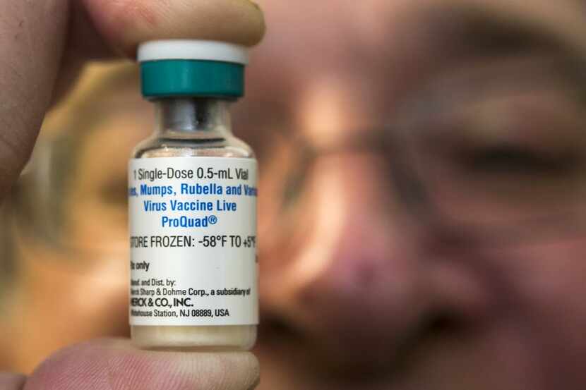 A pediatrician holds a dose of the measles-mumps-rubella (MMR) vaccine at his practice. 