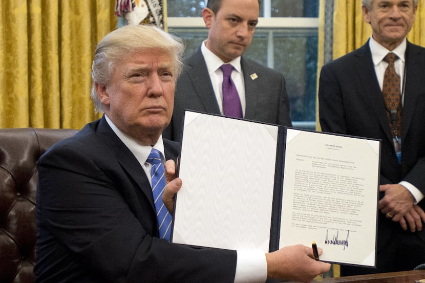 President Donald Trump shows the Executive Order withdrawing the US from the Trans-Pacific...