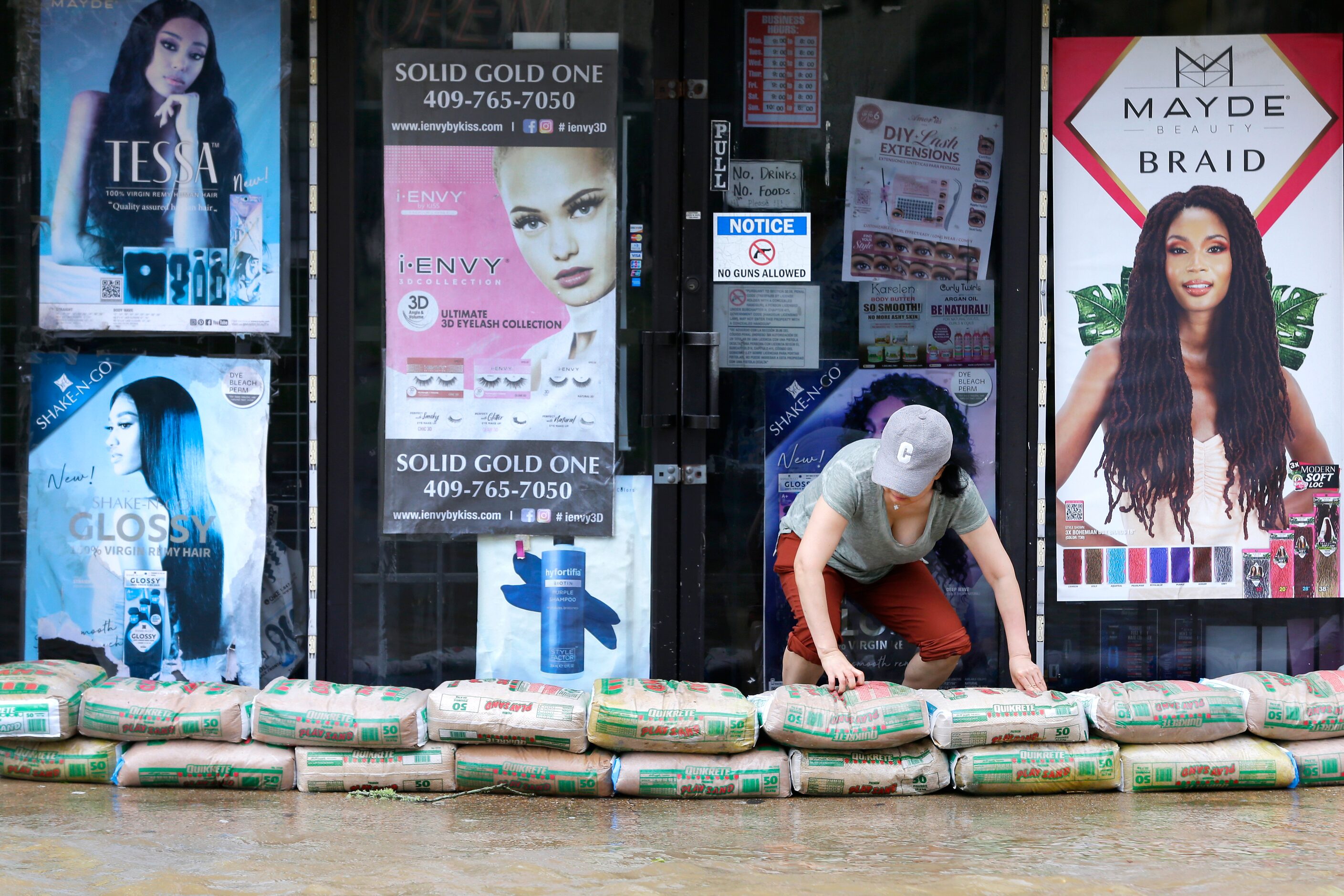 A shop owner piles sandbags around the entrance as street flooding approaches the building...