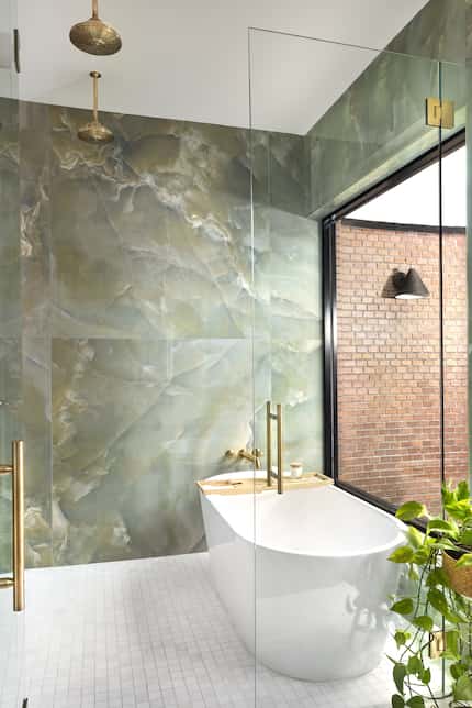 Large soaking tub inside a walk-in shower area with marbled green wall tiles.
