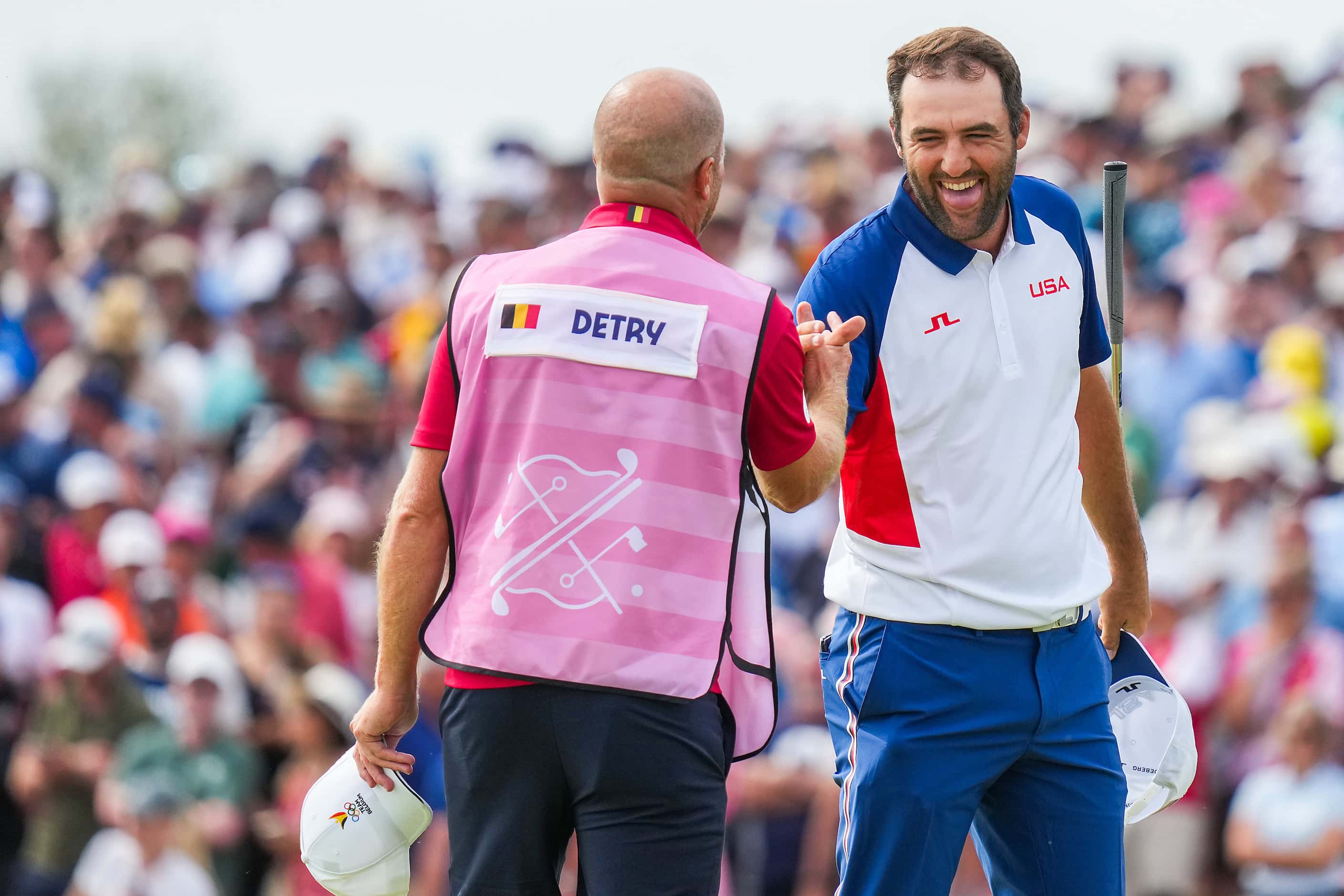 Scottie Scheffler of the United States celebrates with the caddie for Thomas Detry, of...