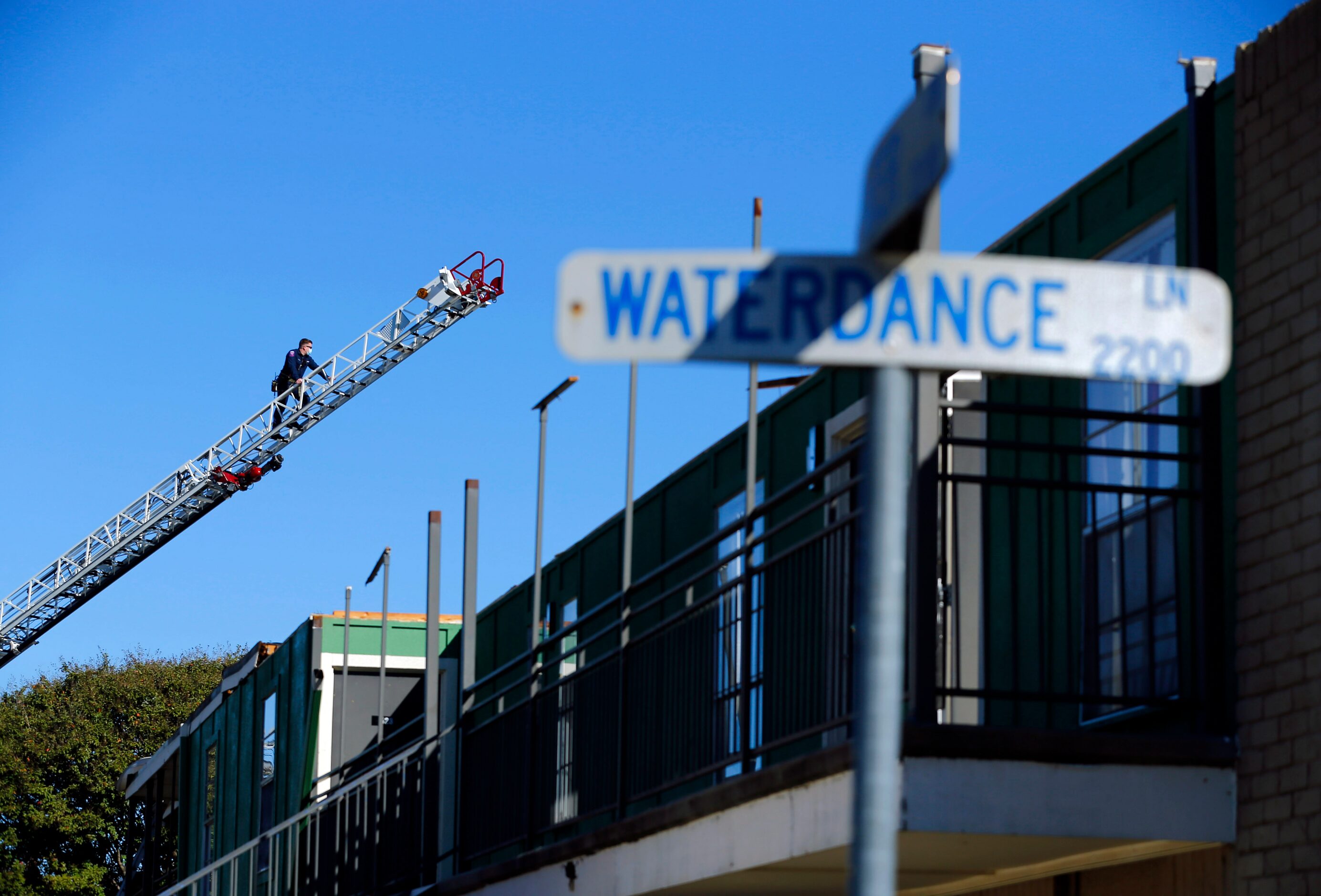 An Arlington firefighter inspects a roofless Waterdance Apartments building that was peeled...